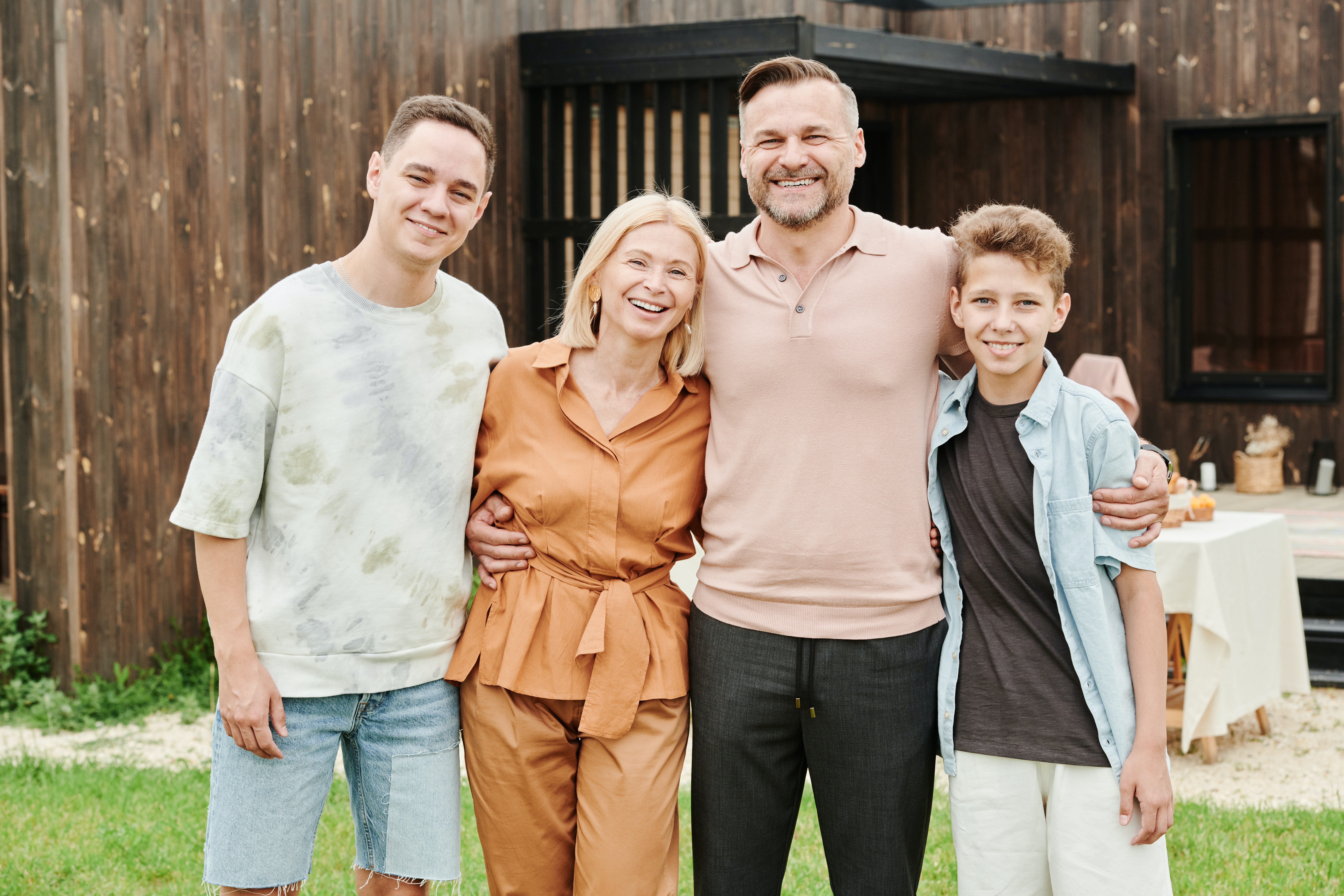 A family of four stands together in front of their house